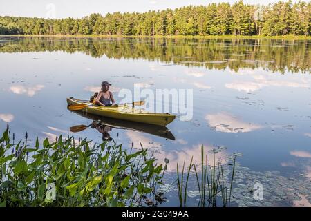 A woman kayaking in Beaver Pond at the Birch Hill Dam Reservation in Royalston, Massachusetts. Stock Photo