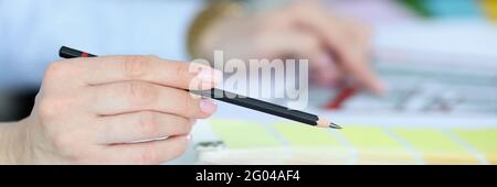 Black pencil in hand over color palette Stock Photo