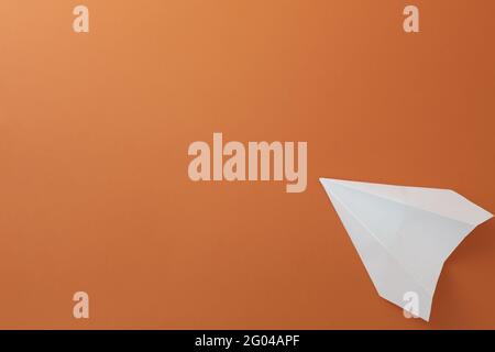 Paper white plane on orange background. Close-up Stock Photo