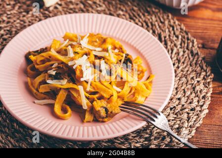 Tagliatelle Pasta with Creamy Pumpkin Sauce and Champignons Garnished with Grated Parmesan Cheese