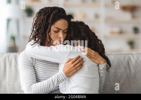 Little black girl crying on mothers shoulder Stock Photo