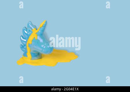 Creative concept made with blue painted unicorn head with yellow paint dripping on a pastel blue background. Minimal pop art fantasy concept. Copy spa Stock Photo