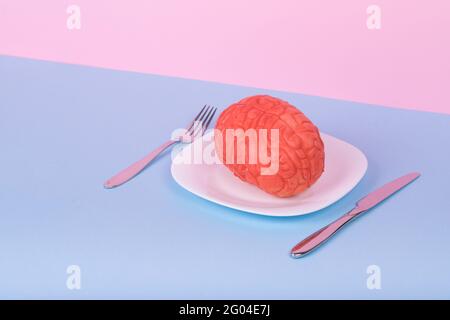 Popular Minimal idea made of the human brain on a plate, fork and knife on a pastel background .Creative concept design of nutrition of smart brain ed Stock Photo