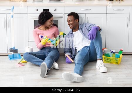 Relaxed african american family sitting on floor with cleaning tools Stock Photo