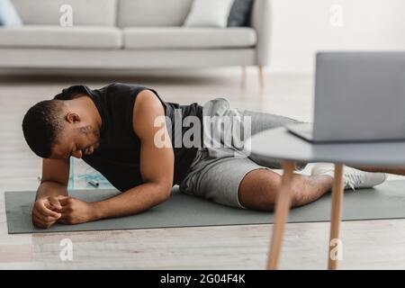 Sporty Black Man Feeling Bad During Online Workout At Home Stock Photo