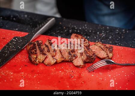 Chopped into slices of Grilled juicy marbled beef with pepper and salt on cutting board close-up. Selective focus. Stock Photo