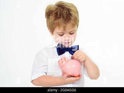 Little boy put coin in piggy bank. Saving money concept. Finance. Child with moneybox. Bank advertising. Stock Photo