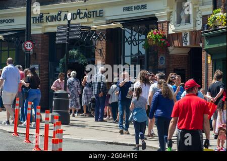 Windsor, Berkshire, UK. 31st May, 2021. People queue for the Wetherspoon King and Castle pub. Windsor was packed with locals and visitors today as the warm sunshine brought people into the town for the Bank Holiday Monday. Following the lifiting of most of the Covid-19 restrictions the town was booming today with people eating outside, going on river trips and enjoying time with their families and friends. Credit: Maureen McLean/Alamy Live News