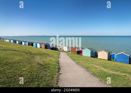 A row of colourful beach huts along the grassy banks of Tankerton Slopes overlooking the beach, just outside Whitstable, North Kent coast, England, UK Stock Photo