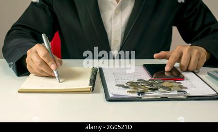 Close-up of a man writing financial notes on his desk, including financial and accounting documents. Stock Photo