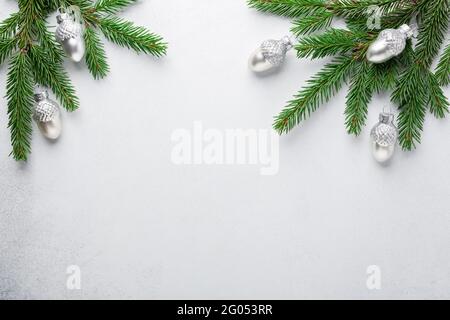 Christmas composition. Fir tree branches with silver decorative oaks on stone background. Top view. Copy space - Image Stock Photo