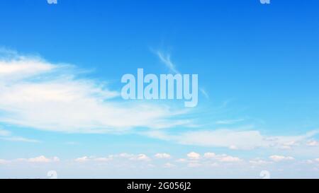 Blurred white clouds floating in the blue sky for use as a banner, poster or wallpaper. Stock Photo