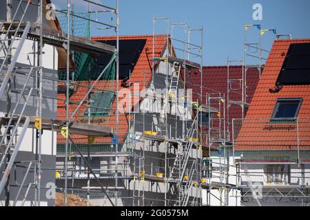 Nieder Erlenbach, Germany. 31st May, 2021. Scaffolding stands on the houses of a new housing estate in Frankfurt's Nieder-Erlenbach district. Experts are critical of the development of grassland in Hesse. (to dpa 'Land consumption in Hesse') Credit: Boris Roessler/dpa/Alamy Live News Stock Photo