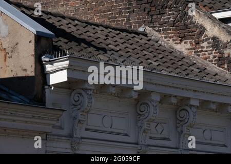 Facade of an old house with thin and sharp needles on top of the decorative weathered gutter to prevent birds (pigeons) from sitting here Stock Photo