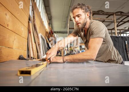 Man using a utility knife on a workbench Stock Photo