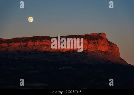 Pessonada Cilffs, in Conca de Tremp, at sunset with the full moon rising (Pallars Jussà, Lleida, Catalonia, Spain, Pyrenees) Stock Photo