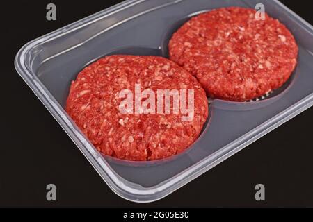 Round raw burger patties in package on dark background Stock Photo