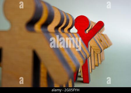 Activist stand out from the crowd concept. The red figurine is in the line of others. Stock Photo