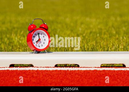 Red alarm clock on the running track in the stadium Stock Photo