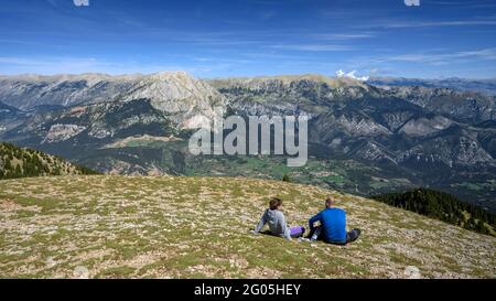 Hikers in the Gallina Pelada summit, the highest point of Serra d'Ensija, looking towards the Pedraforca and Cadí south faces (Berguedà, Catalonia) Stock Photo