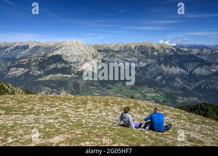 Hikers in the Gallina Pelada summit, the highest point of Serra d'Ensija, looking towards the Pedraforca and Cadí south faces (Berguedà, Catalonia) Stock Photo