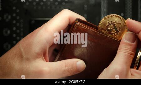 Physical Bitcoins (BTC) put into the wallet on the motherboard digital chip background, cryptocurrency and digital wallet concept Stock Photo