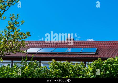 Solar panels on red roof of a house generating environmental friendly energy for the building to save the planet Stock Photo