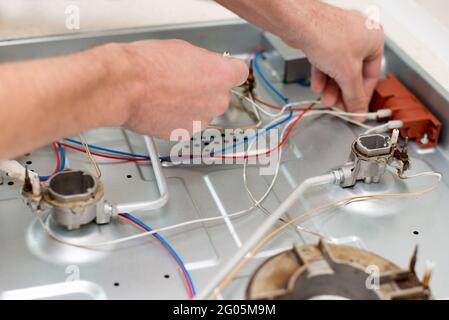 Photo Of repairmans hands examining stove in kitchen Stock Photo