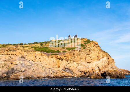 Ancient ruins of Temple of Poseidon on the cliff, Sounion - distant view from the sea in sunny summer day, with crystal blue sky, Greece Stock Photo
