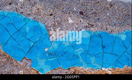 Blue peeling paint on the wall. An old concrete wall with cracked, peeling paint. Weathered rough painted surface Stock Photo