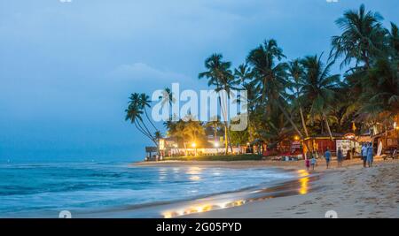 Panoramic view of people walking along beach after sunset, Hikkaduwa, Southern province, Sri lanka Stock Photo