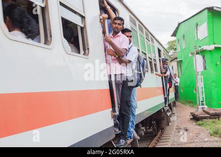 Sri Lankan train passengers jammed into doorway entrance of rail carriage, Colombo, Sri Lanka Stock Photo