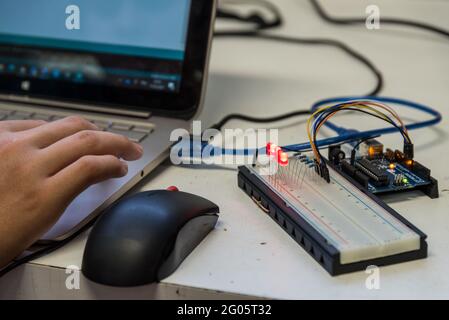 Skilled Worker Works On A Laptop With Electrical Engineering Components Stock Photo