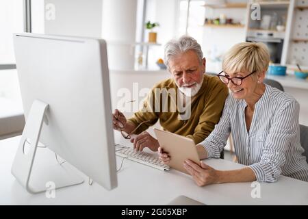 Cheerful senior couple using technology devices and having fun at home Stock Photo