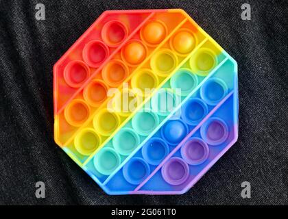 New popular silicone colorful antistress pop it toy for child on black background. View from above. Copy space. Simple dimple Stock Photo