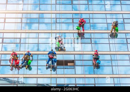Industrial climbers cleaning the exterior facade of the rear glass of a skyscraper Stock Photo