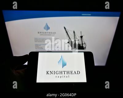 Person holding smartphone with logo of investment adviser Knighthead Capital Management LLC on screen in front of website. Focus on phone display. Stock Photo