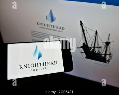Person holding mobile phone with logo of investment adviser Knighthead Capital Management LLC on screen in front of web page. Focus on phone display. Stock Photo