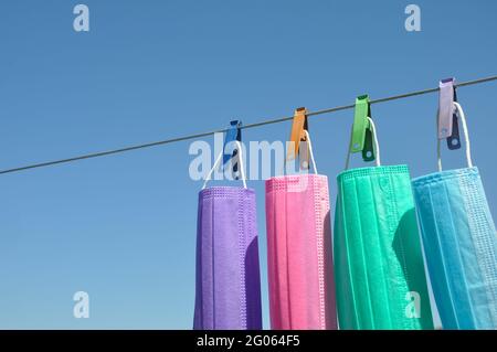 Concept of protect environment from waste and pollution with negative space, Photo of multi colored surgical face mask (Disposable mask) hanging on clothesline wire with clothespin. Stock Photo