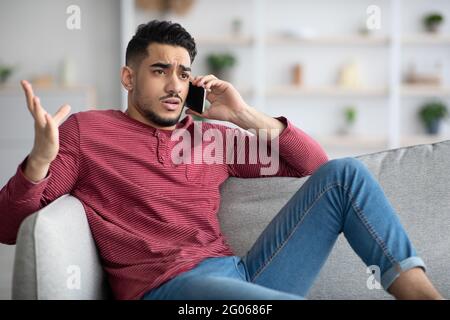Irritated arab guy having conversation on phone Stock Photo