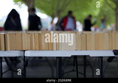 Bookstall in outdoor market with blurred people and trees in background Stock Photo