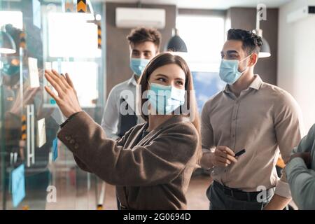 Colleagues having meeting using sticky notes on glass wall Stock Photo
