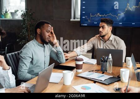 Sick young black male worker suffering from headache Stock Photo
