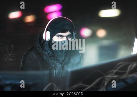 Hacker in the office with headphones with microphone in search of prey. Steals data and copy of Bank from His Underground Hideout Stock Photo