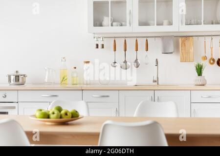 Simple kitchen, scandinavian design. Metal pan on stove, various kitchen utensils and kitchenware in cupboard Stock Photo