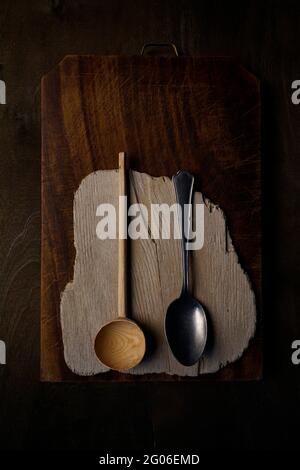 Old kitchen tools on a used wooden cutting board and a dark wooden background Stock Photo