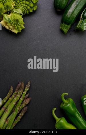 Organic green raw vegetables on black slate background with space for text, top view, healthy eating Stock Photo