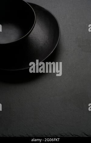 Empty black bowl and plate on a slate stone with space for text Stock Photo