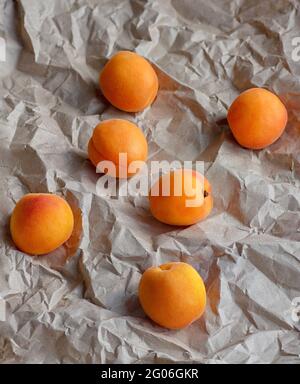 Ripe juicy apricots on the background of crumpled wrapping paper. Vertical crop. Close up. Stock Photo
