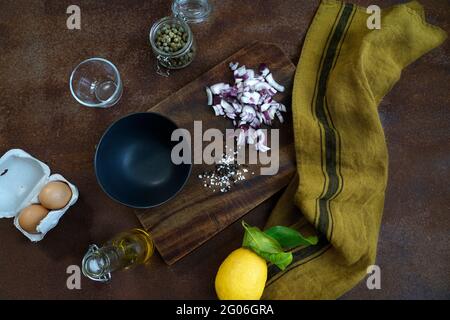 Ingredients for the preparation of beef tartare on an old wooden cutting board, kitchen fabric and rusty metal background, flat lay, Italy, Europe Stock Photo